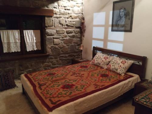 Vlácha的住宿－Παραδοσιακή πέτρινη κατοικία στην Βλάχα Ελάτης，一间卧室配有一张红色棉被的床