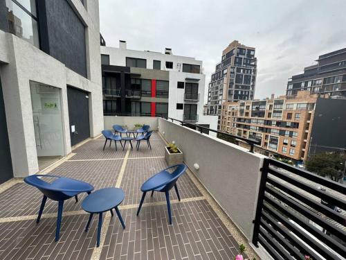 een balkon met blauwe stoelen en tafels in een gebouw bij Aparta-estudio dotado para estrenar in Bogota