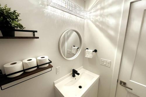 a white bathroom with a sink and a mirror at Exquisite, bright & modern condo. in Niagara Falls