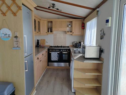 a small kitchen with wooden cabinets and a stove at Dog Friendly 8 Berth Lodge, 600 Yard's From The Beach In Hunstanton in Hunstanton