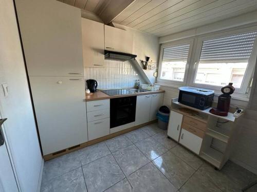 une petite cuisine avec des armoires blanches et un évier dans l'établissement Duplex F2 - proche GARE TGV, à Mulhouse