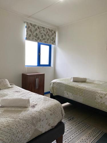 um quarto com 2 camas e uma janela em Lodging Incógnita, Punta Arenas em Punta Arenas