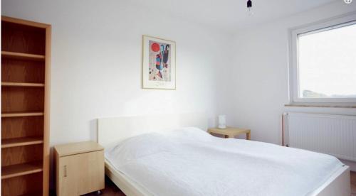 a white bedroom with a bed and a window at Ferienwohnung Tannen-Apotheke Eins in Mengerskirchen