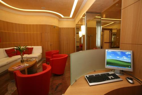 a office with a computer on a desk with red chairs at Le Petit Hotel in Turin