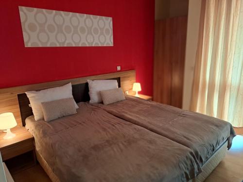 a bedroom with a large bed with a red wall at Apartment Wintermärchen Bansko 4* in Bansko