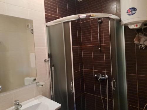 a bathroom with a shower with a sink and a mirror at Apartment Wintermärchen Bansko 4* in Bansko