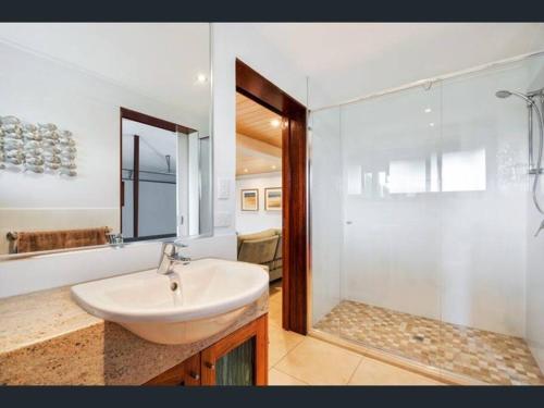 a white bathroom with a sink and a shower at A place to relax in Mudjimba