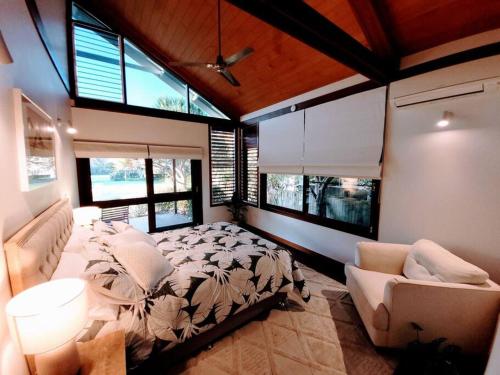 a bedroom with a bed and a couch and windows at A place to relax in Mudjimba