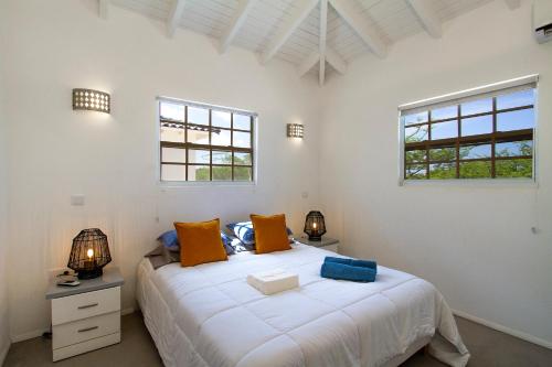 a bedroom with a large white bed with two windows at Villa Jewel - Viva Bonaire in Kralendijk