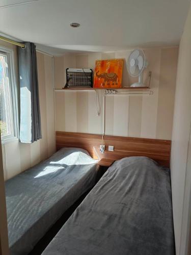 une petite chambre avec deux lits et une fenêtre dans l'établissement MOBIL HOME LMNP GUIGON, à La Roque-dʼAnthéron