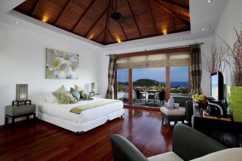 - une chambre avec un lit blanc et un salon dans l'établissement Baan Phu Prana Boutique Villa, à Surin Beach