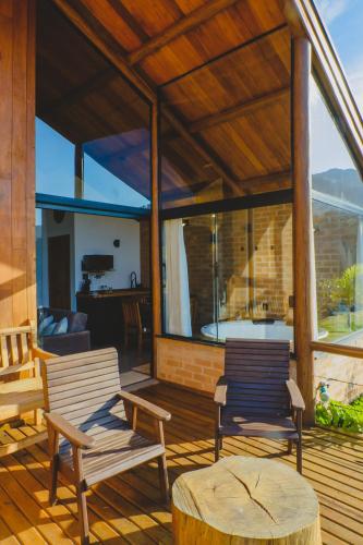 two chairs and a table on a wooden deck at Pousada Ho'oponopono Chalets & Wine in Sapucaí-Mirim