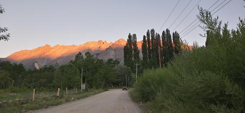 une voiture parcourant une route avec des montagnes en arrière-plan dans l'établissement La Casa de los Cuadros, à Lago Puelo