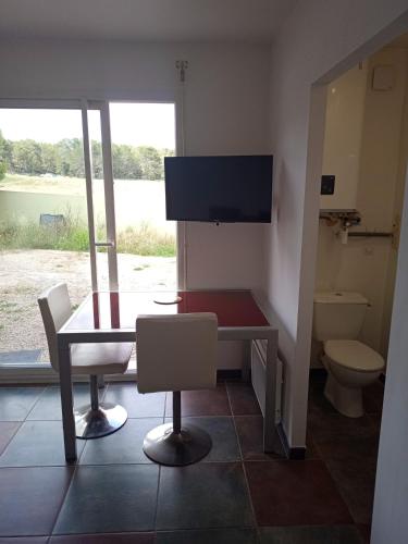 Habitación con mesa, aseo y TV. en Studio cosy, en Nimes