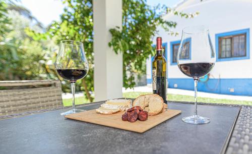 two glasses of wine and a cutting board with cheese and bread at Quinta de São Pedro in Sobreda