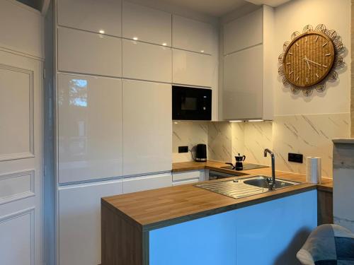 a kitchen with a sink and a clock on the wall at Charmante petite maison in Saint-Vigor-le-Grand