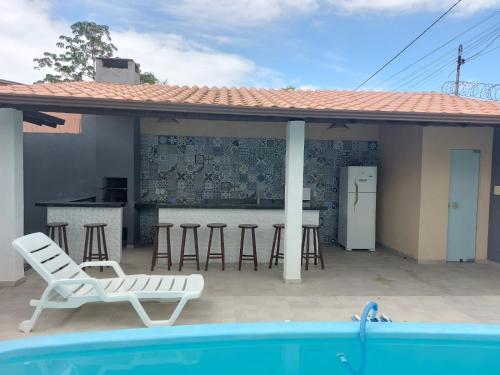 聖克魯斯－卡布拉利亞的住宿－Casa individual com piscina e area gurmet，一个带酒吧和凳子的庭院,毗邻一个游泳池