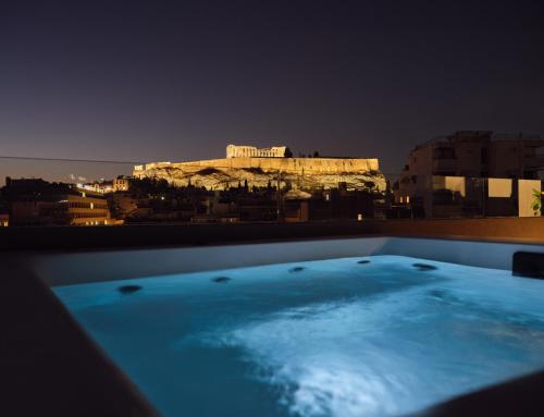 a bath tub with a view of the acropolis at night at Urban Stripes Athens in Athens