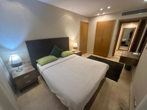 sypialnia z dużym białym łóżkiem z zielonymi poduszkami w obiekcie Scarab ES 03 GF One Bedroom Gouna w mieście Hurghada