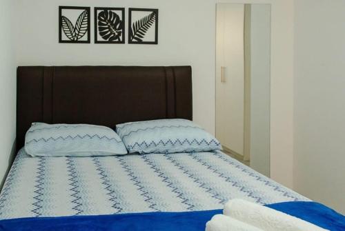 1 cama con sábanas azules y blancas y 2 almohadas en Geribá Beach Apart Hotel apt504, en Búzios