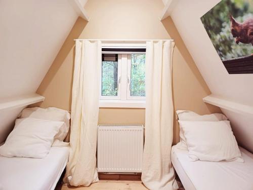 a attic room with two beds and a window at A Wood Lodge - zwembad - relax - natuur in Durbuy
