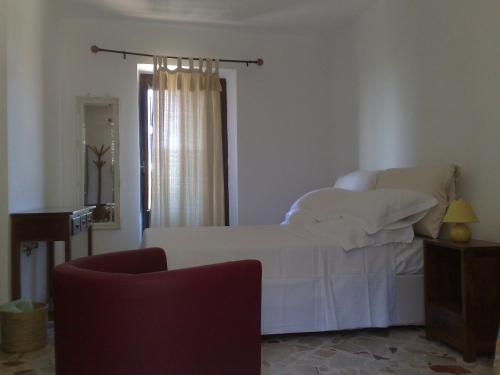 a bedroom with a white bed and a chair at La Locanda Di Cadì in Petralia Soprana