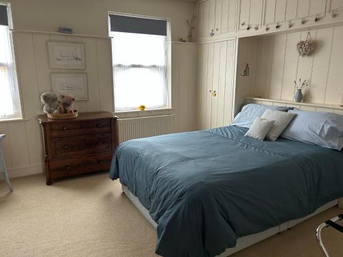 a bedroom with a bed and a dresser and two windows at Magical, Stylish, Comfortable, Brilliant Location in Kent