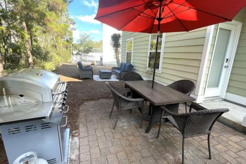 a patio with a grill and a table with an umbrella at Grayling Beach House in Inlet Beach