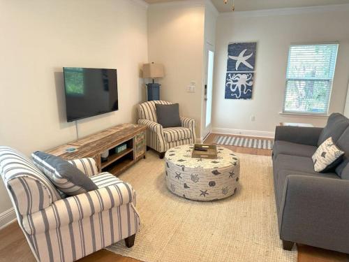 a living room with couches and a flat screen tv at Grayling Beach House in Inlet Beach