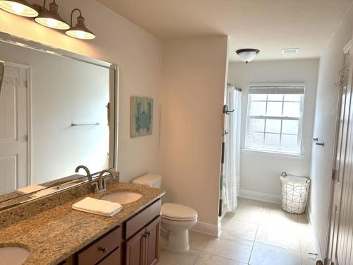 a bathroom with a sink and a toilet and a mirror at Grayling Beach House in Inlet Beach