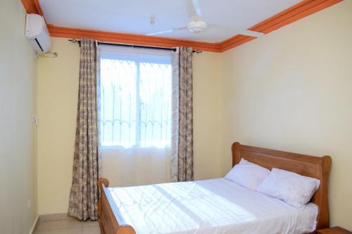 1 dormitorio con 1 cama y una ventana con cortinas en Bahari Pride Apartment, en Mombasa