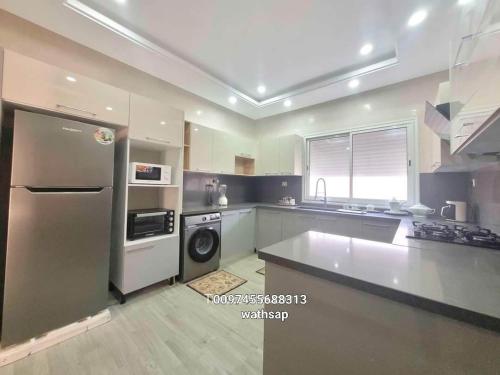 a kitchen with a stainless steel refrigerator and a dishwasher at VILLA AZDEN in Al Maqārisah