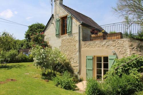 uma antiga casa de pedra com portas verdes e uma varanda em Gîte de charme au cœur du saumurois 