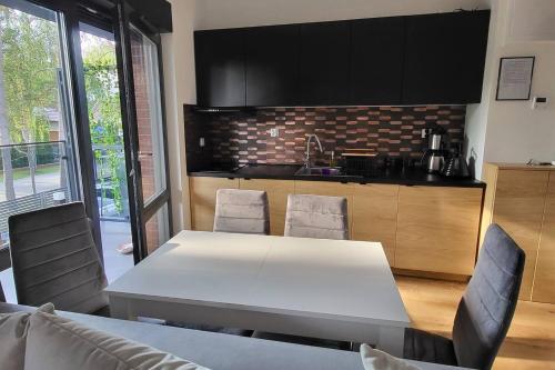 una cocina con mesa blanca y sillas. en Modrzewiowa Apartament z 1 sypialnią, en Niechorze