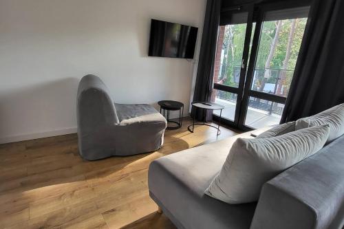 una sala de estar con un sofá y una silla en Modrzewiowa Apartament z 1 sypialnią, en Niechorze
