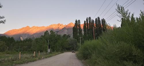 a car driving down a road with mountains in the background at La Casa de los Cuadros in Lago Puelo