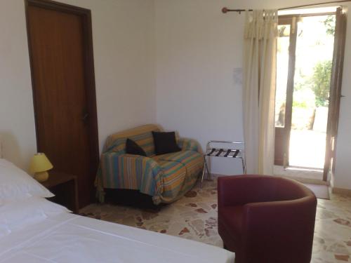 a bedroom with a bed and a chair and a window at La Locanda Di Cadì in Petralia Soprana
