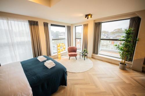 een slaapkamer met een bed en een stoel en grote ramen bij Alphabet Studio Apartments including City view in Hilversum