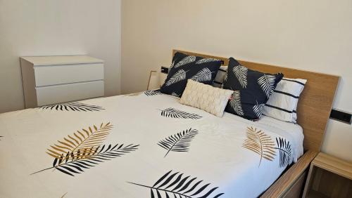 a bed with a black and white comforter with leaves at Apartamento Sabaris Playa in Baiona