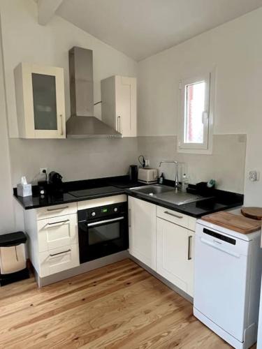La cuisine est équipée de placards blancs et d'un four avec plaques de cuisson noires. dans l'établissement Chalet Cosy, à Lège-Cap-Ferret