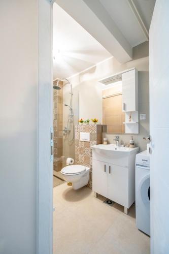 a white bathroom with a toilet and a sink at Calendula apartments in Tuzla