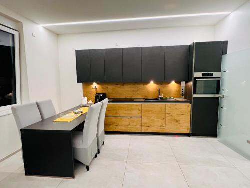 a kitchen with black cabinets and a table and chairs at Appartement - Rue du Canal in Esch-sur-Alzette