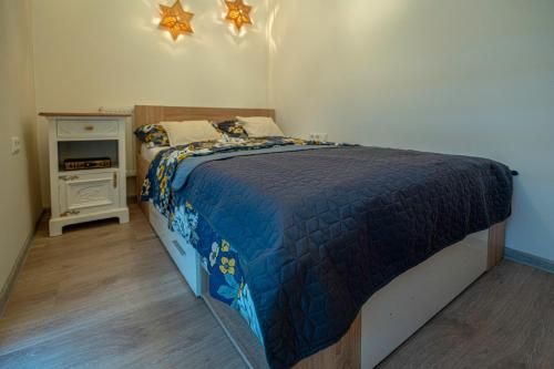 een slaapkamer met een bed met een blauw dekbed bij Calendula apartments in Tuzla