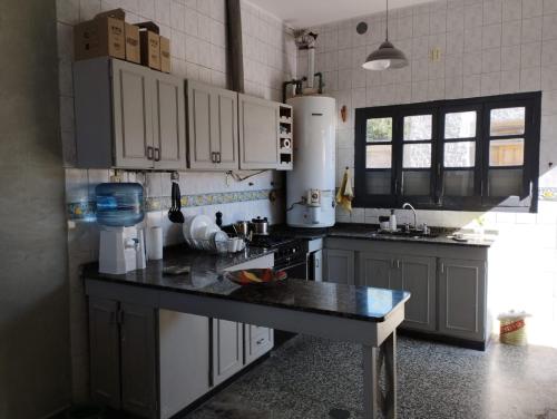 uma cozinha com armários brancos e um balcão preto em HOSTAL HOUSE REYMON,habitaciones privadas" precio por persona" em Mendoza