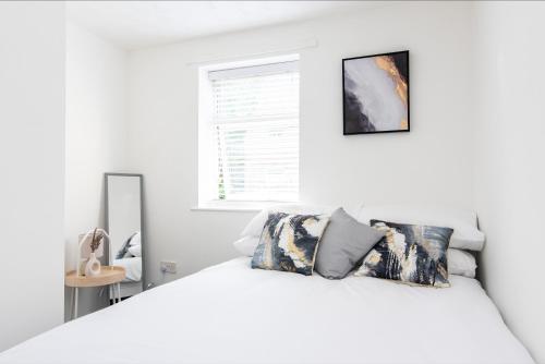 a white bedroom with a white bed and a window at South Street Apartments in Derby