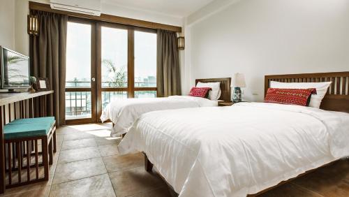 a bedroom with two beds and a large window at Green Tiger House in Chiang Mai