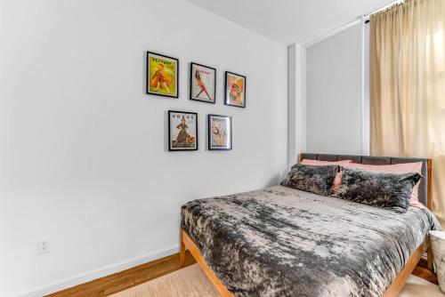 a bedroom with a bed with four pictures on the wall at Welcome to “Sunny Park Slope Retreat”! in Brooklyn