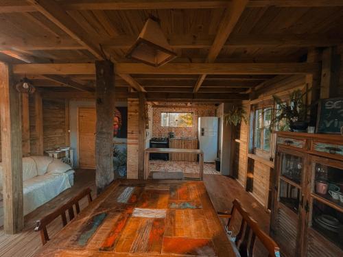 a dining room with a wooden table in a cabin at Pousada Vale da Magia in Praia do Rosa