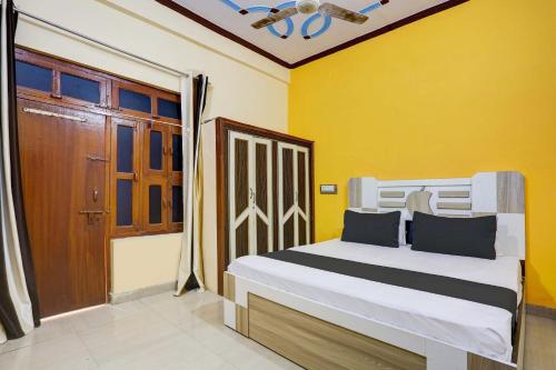 a bedroom with a bed and a yellow wall at OYO Flagship Hotel Suraj Villa in Nārnaul