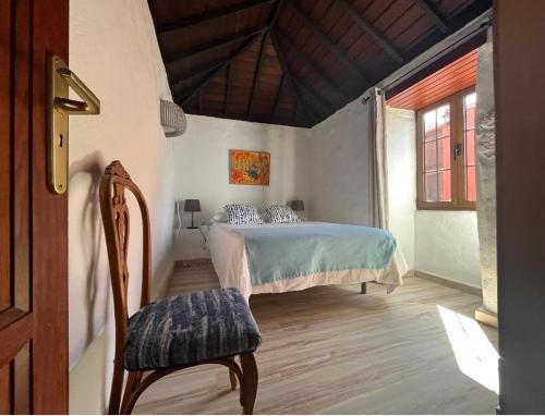 een slaapkamer met een bed en een stoel in een kamer bij Finca La Calzada in Los Quemados